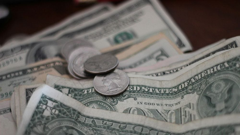 A few coins on top of several one dollar bills