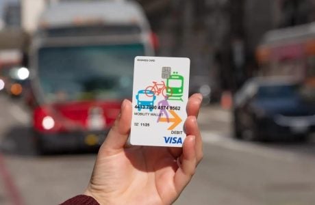 a hand holds a Mobility Wallet card as a bus approaches in the background|family of two kids and two fathers looking happy