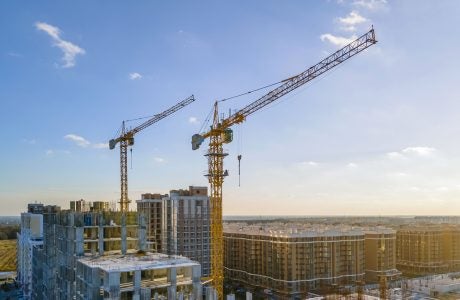 Cranes on the construction site surrounded by new real estates. Scenic aerial photo of growing city districts