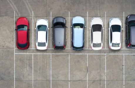 Aerial view of a parking lot with a row of cars and another row of empty parking spaces.