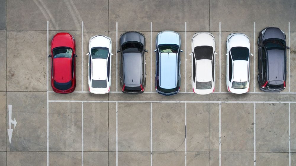 Aerial view of a parking lot with a row of cars and another row of empty parking spaces.