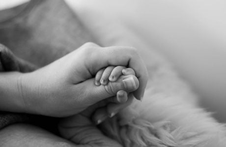 adult hand holding baby's hand