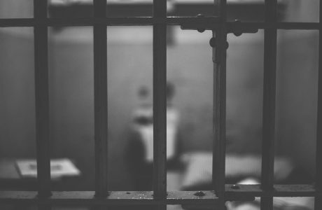 black and white shot of prison cell behind bars