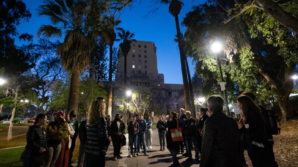 park lighting glows in the background as a group of people gather in an urban park in Los Angeles