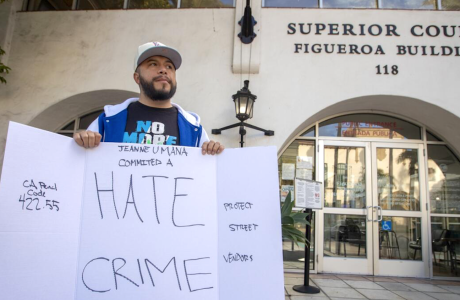 Man in hat holding sign that says "Hate Crime"