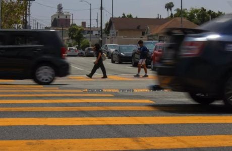 children in a crosswalk as cars speed by