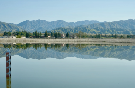 A large body of standing water is visible in the foreground, with mountains in the distance